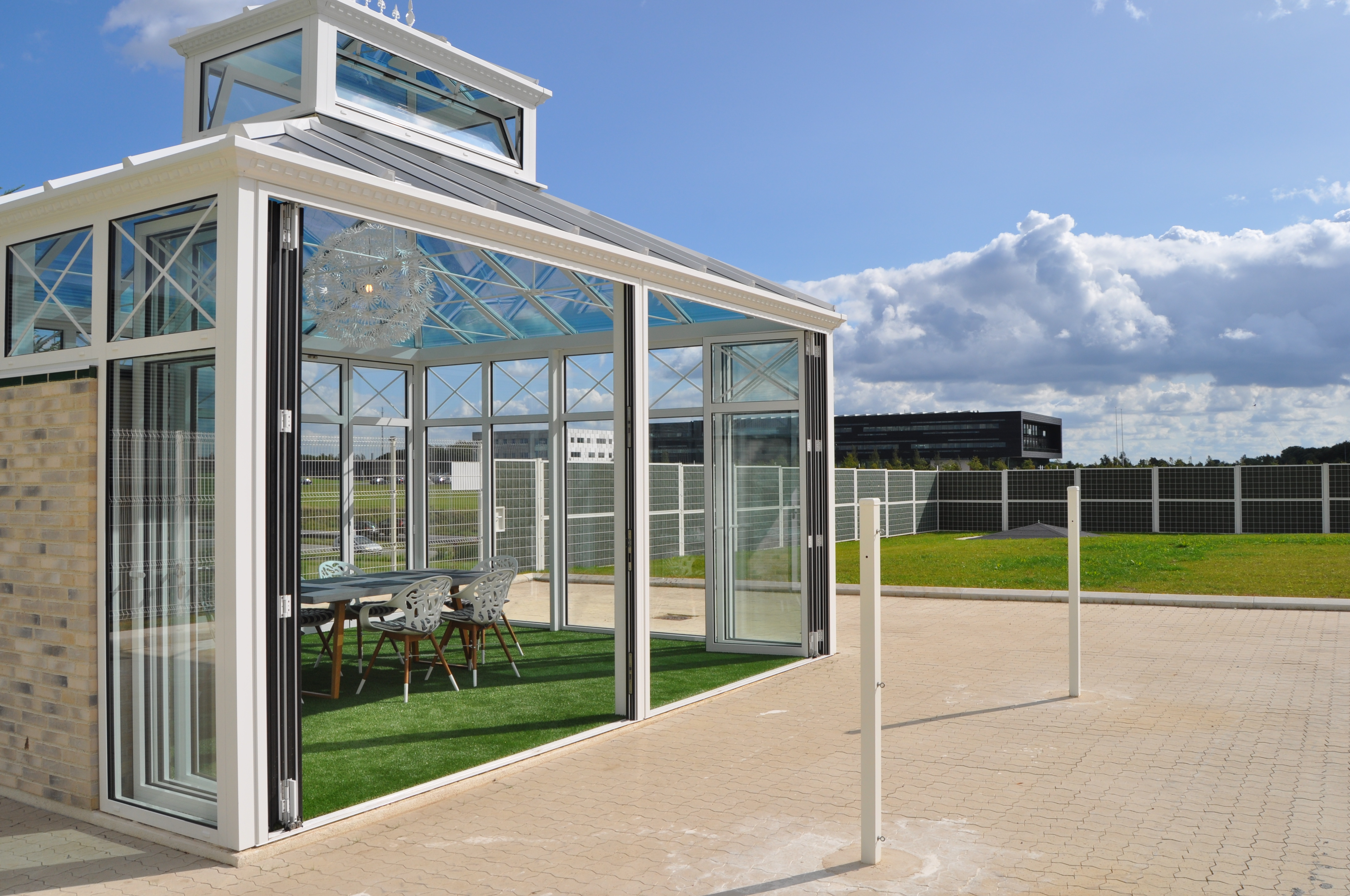 Ein Pavillon mit großen Panoramafenstern in einem Gemeinschaftsbereich eines Unternehmens, abgeschirmt mit dem Noistop® Steel-Lärmschutzzaun von Poda Zaun