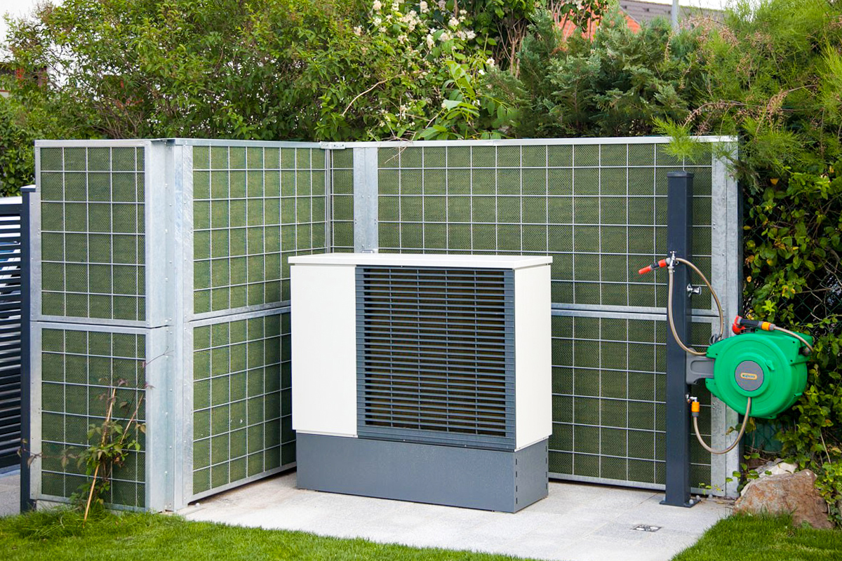 Ein Noistop® Steel-Lärmschutzzaun von Poda Zaun wurde in einem Garten aufgestellt, um den Lärm einer Wärmepumpe abzuschirmen