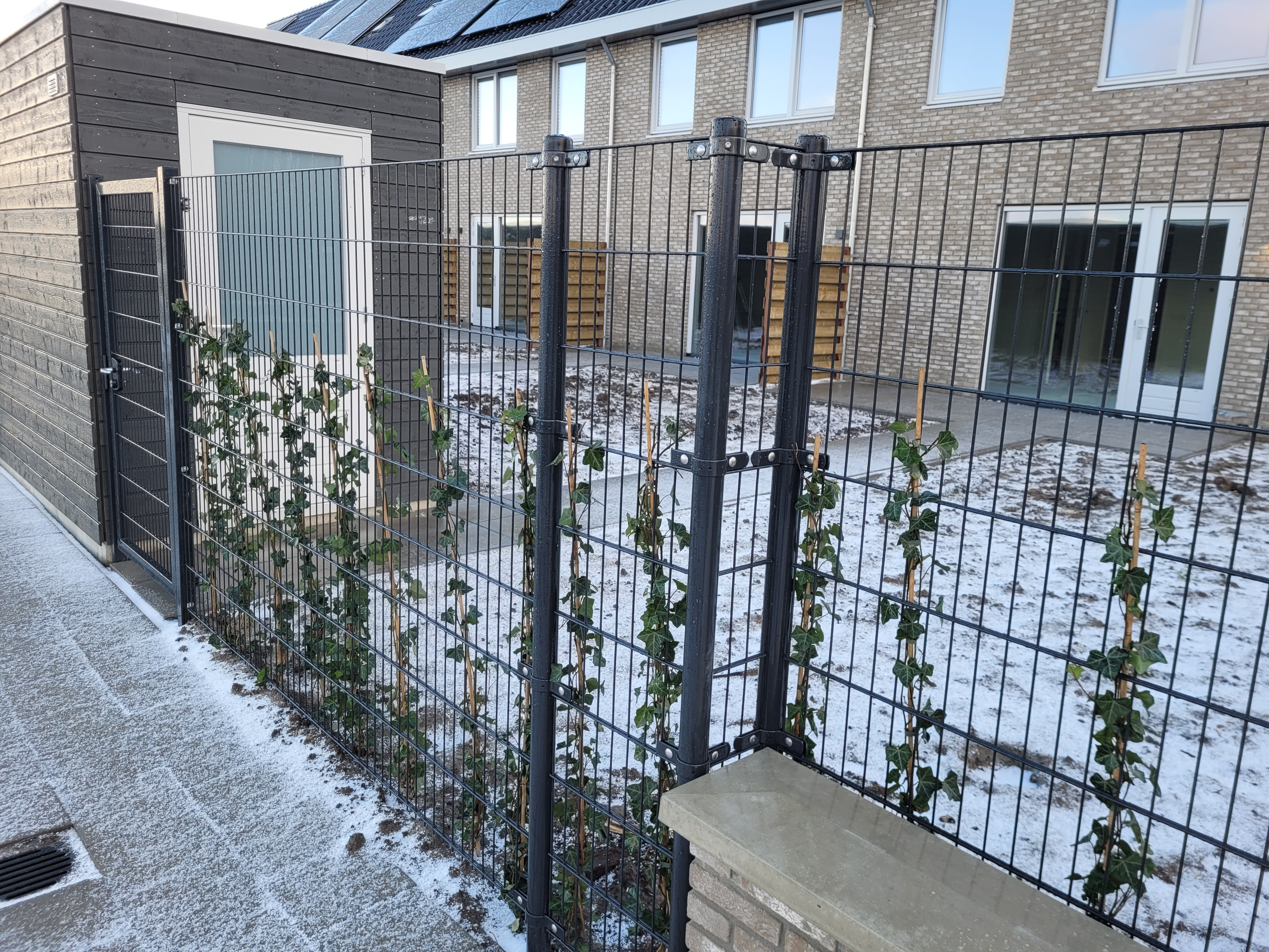 Ein schneebedeckter Garten ist von einem schönen Doppelstabmatten Zaun umgeben