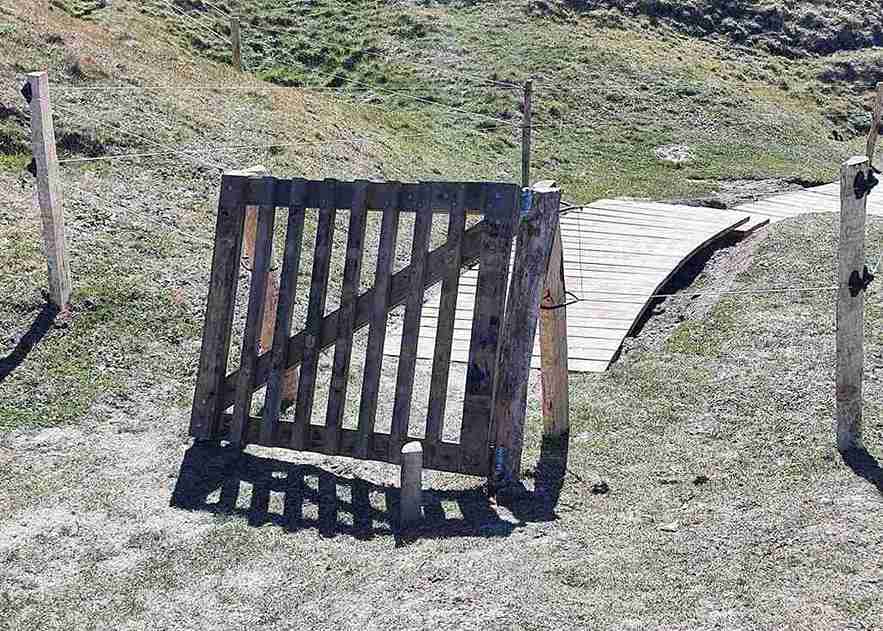 Im Vordergrund ist ein Klappentor zu sehen. Im Hintergrund ist eine Holztreppe zu sehen