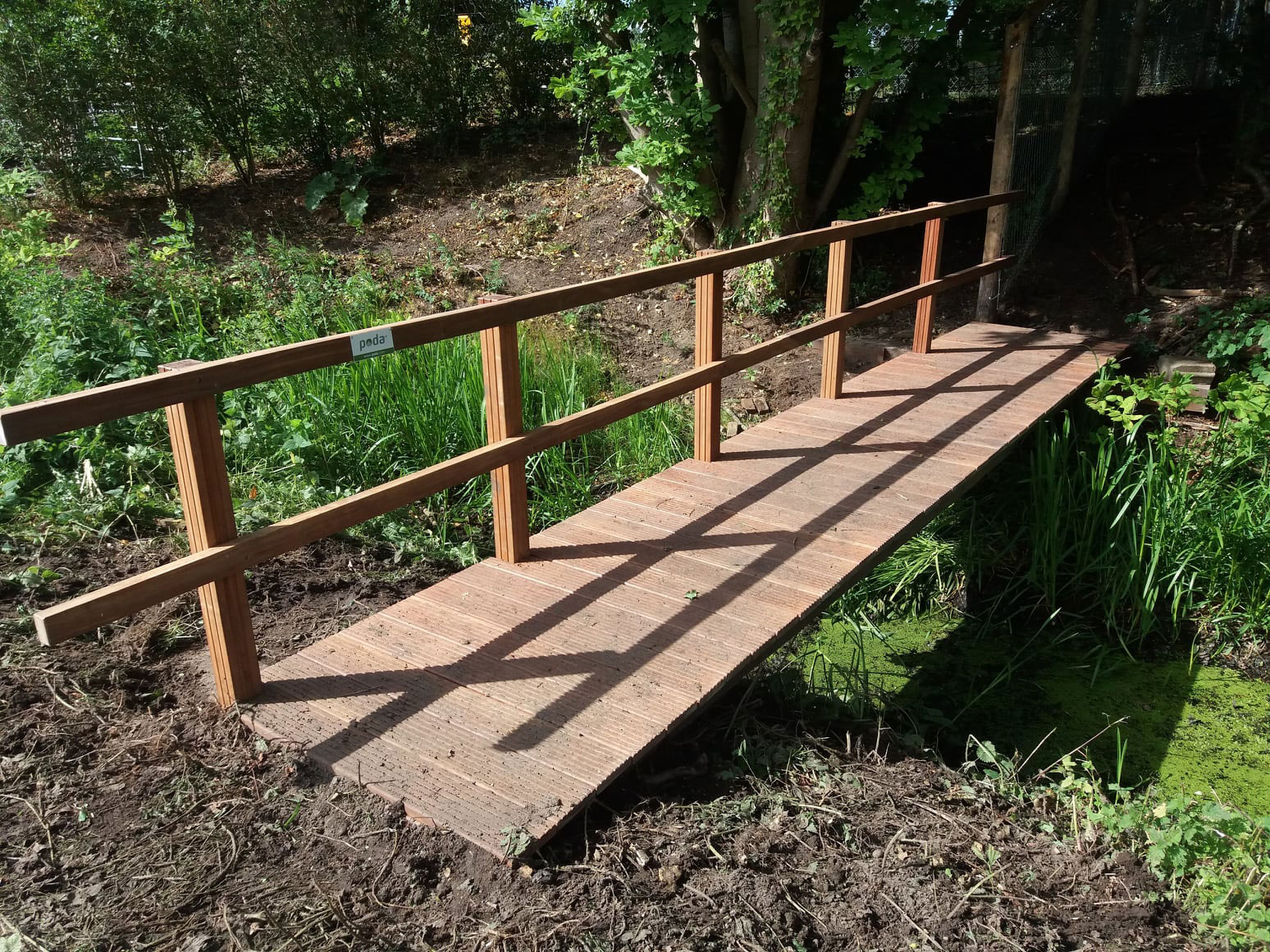 Eine schöne Holzbrücke mit einseitigem Geländer führt Sie sicher über den Fluss