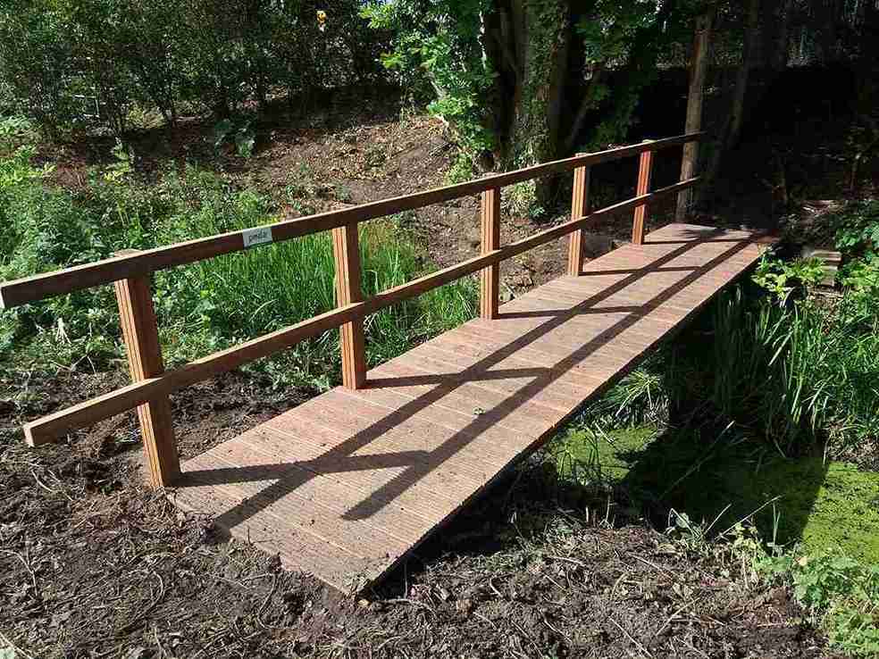 Eine schöne Holzbrücke mit einseitigem Geländer führt Sie sicher über den Fluss