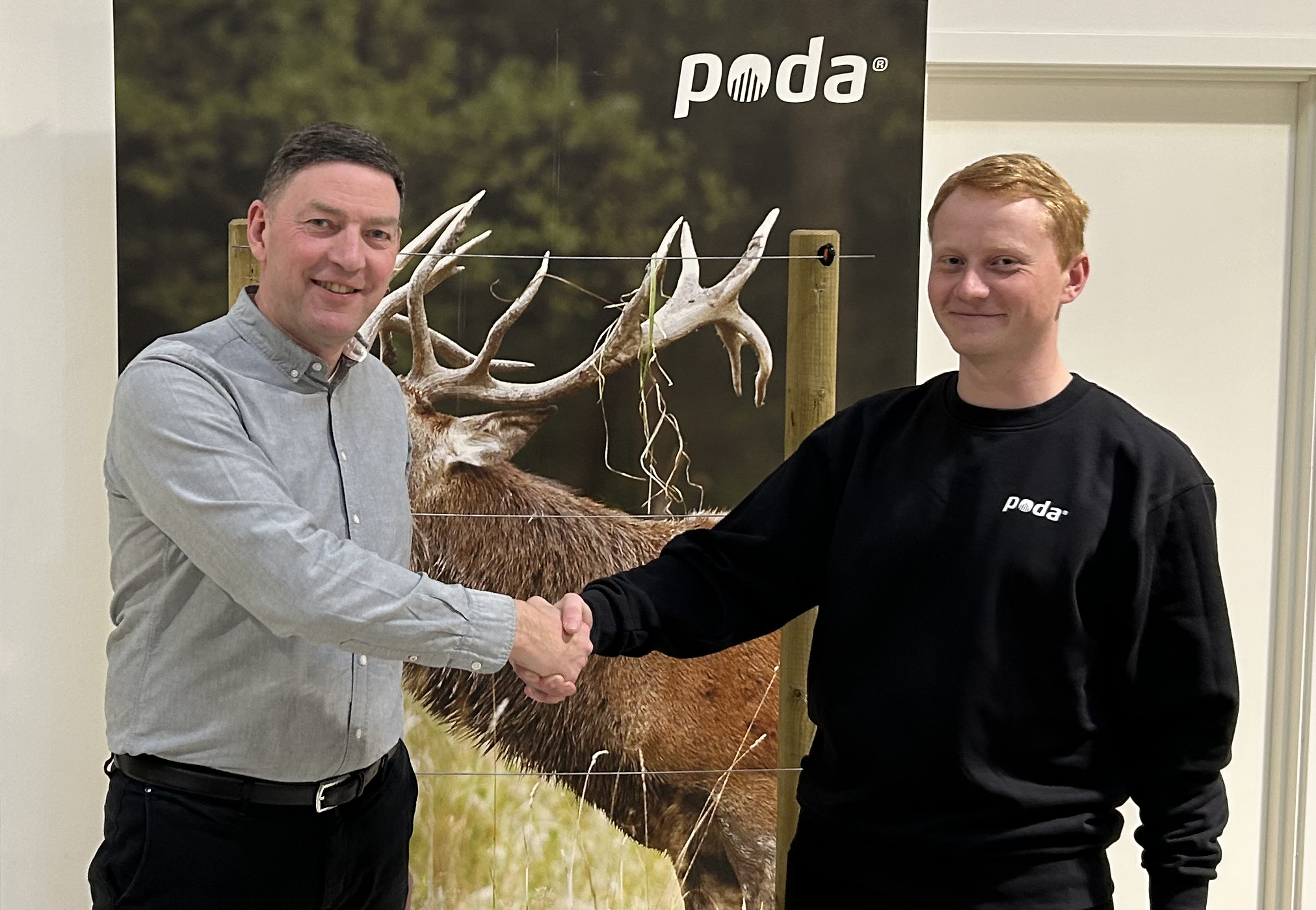 Poda-Direktor Peter schüttelt die Hand von Sofus vom neuen Poda-Zentrum, Poda Hegn Ringe, vor einem Banner mit Rothirsch und Elektrozaun.