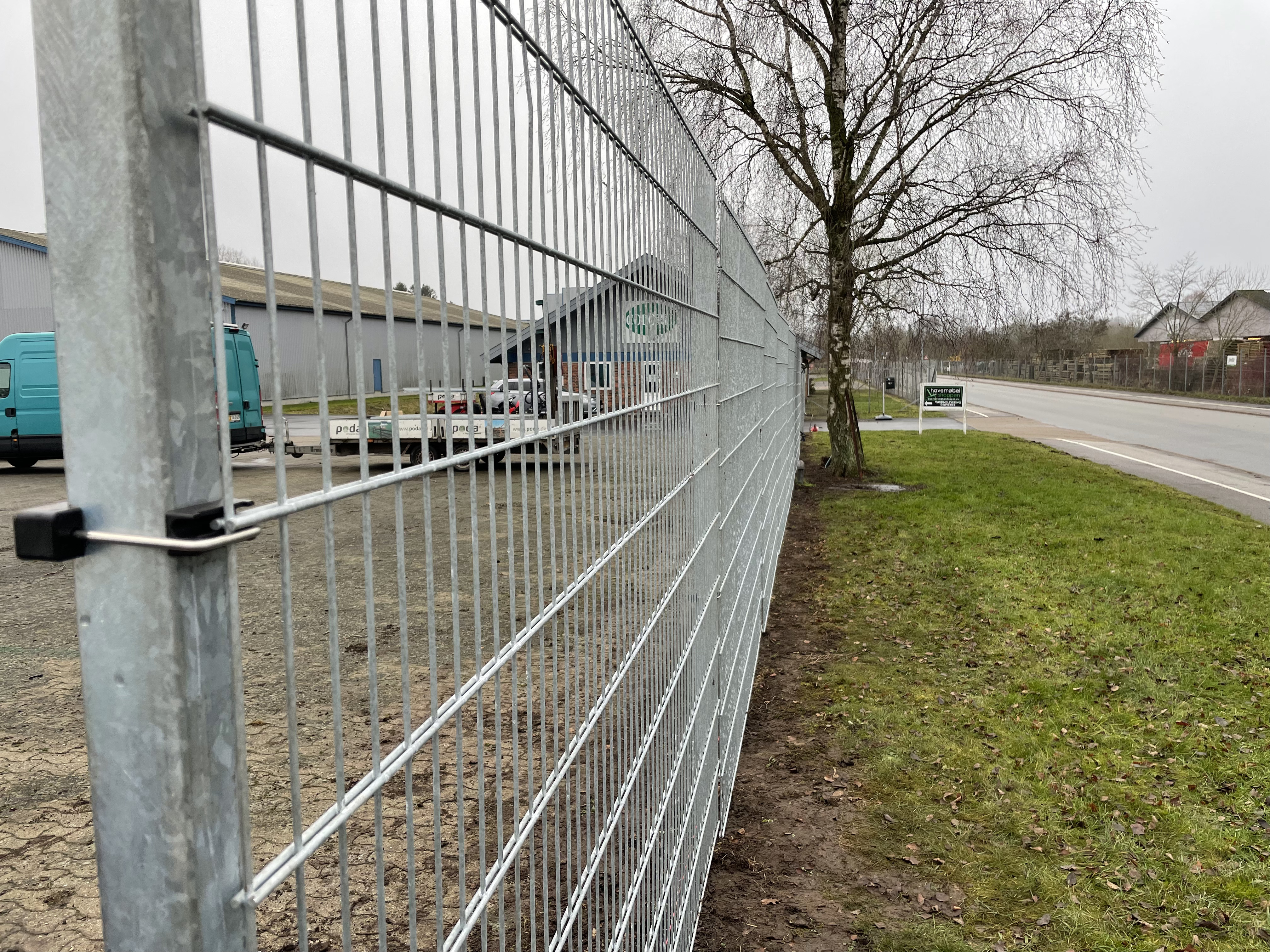 In einem Industriegebiet wird ein grauer Doppelstabmattenzaun zum Schutz eines Unternehmens errichtet.
