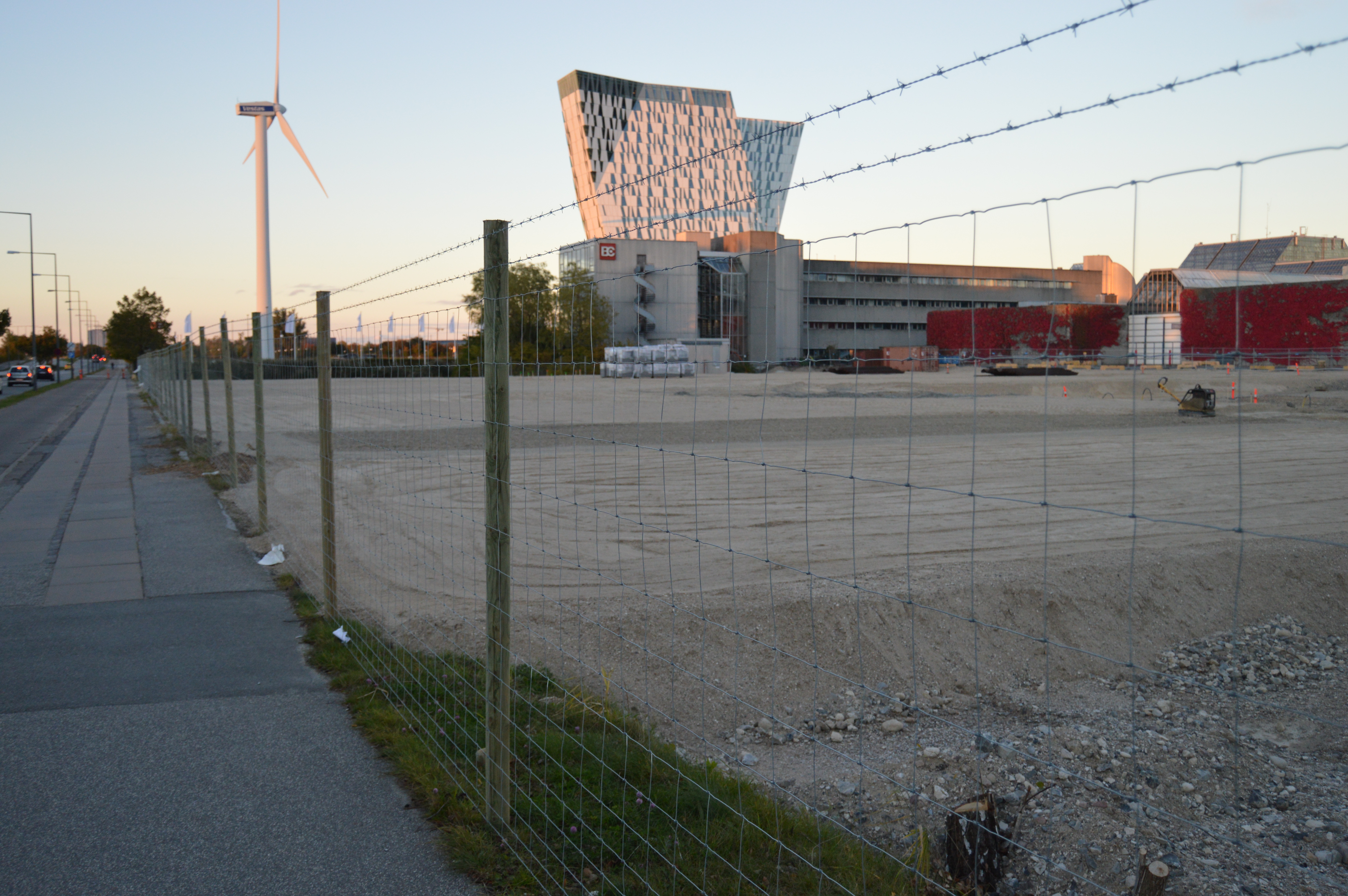 Eine Baustelle wird durch einen Maschendrahtzaun mit zwei Stacheldrähten an der Spitze geschützt