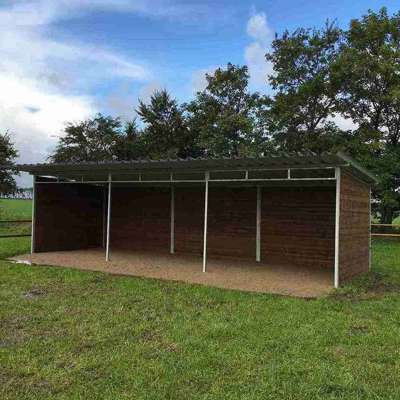 Ein Weidehütt steht inmitten eines Tiergeheges.