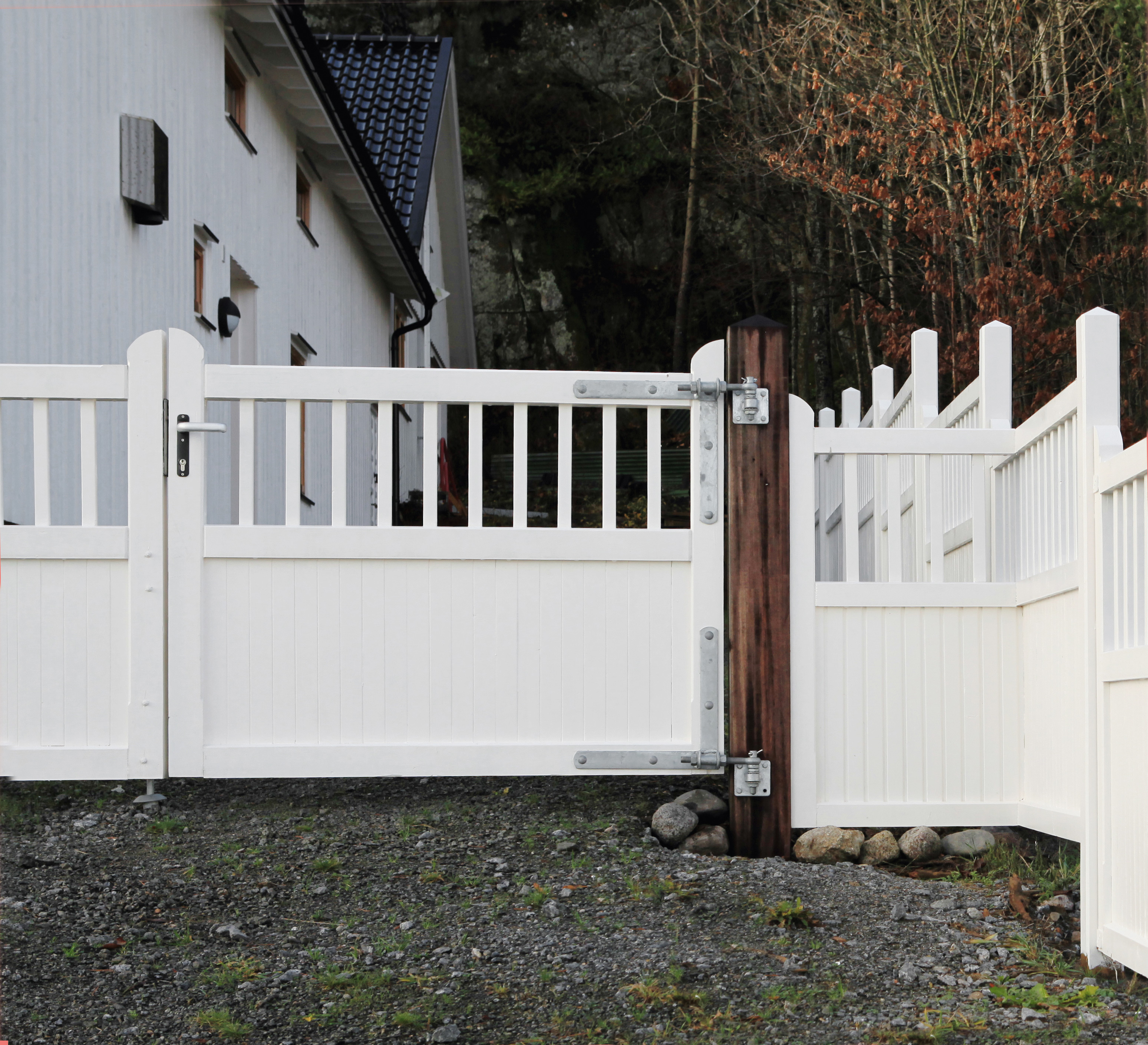 In der Mitte einer Zaunlinie steht ein Country Garden-Tor, das wie der Zaun weiß gestrichen ist.
