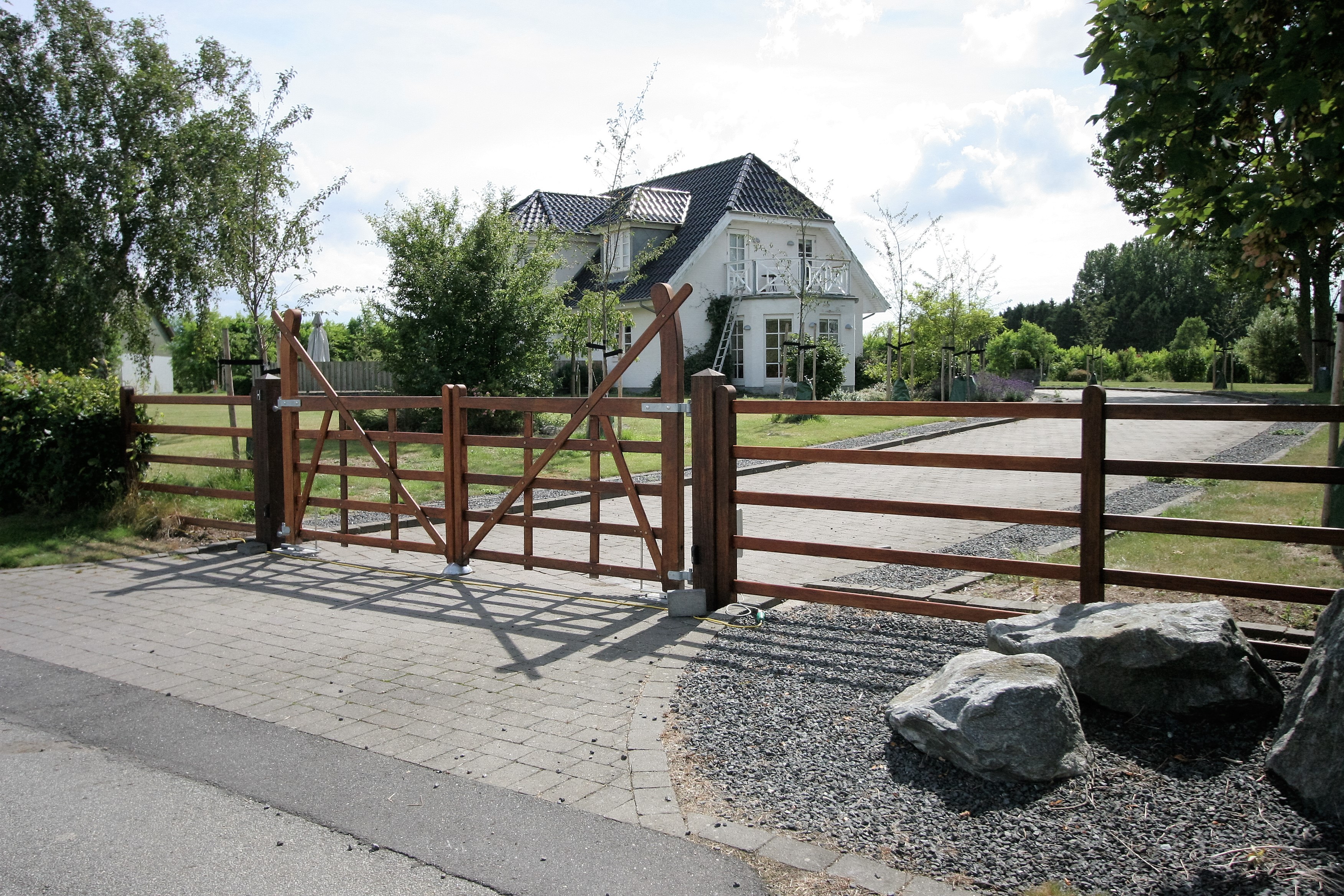 Von einer Straße aus können Sie eine Einfahrt sehen, die mit einem Country Ranger-Tor eingezäunt ist.