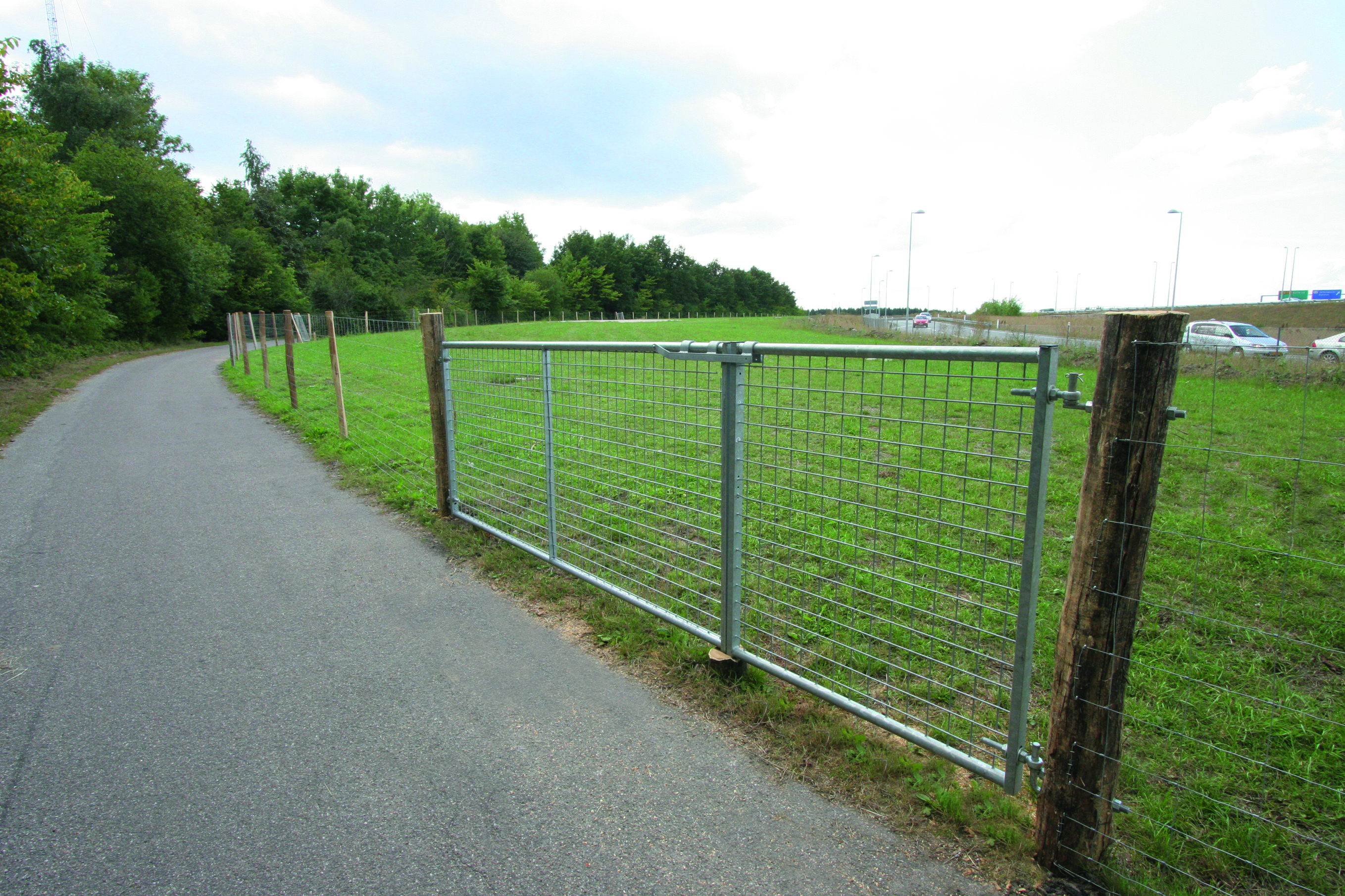 Neben einer Straße befindet sich ein Gehege mit einem Leichtgewichtstor mit einem Gitter als Ein- und Ausgang