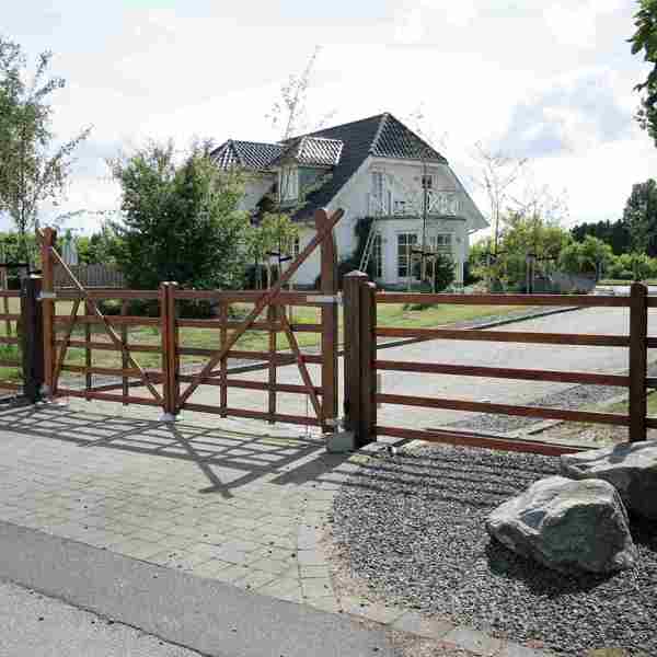 Von einer Straße aus können Sie eine Einfahrt sehen, die mit einem Country Ranger-Tor eingezäunt ist.