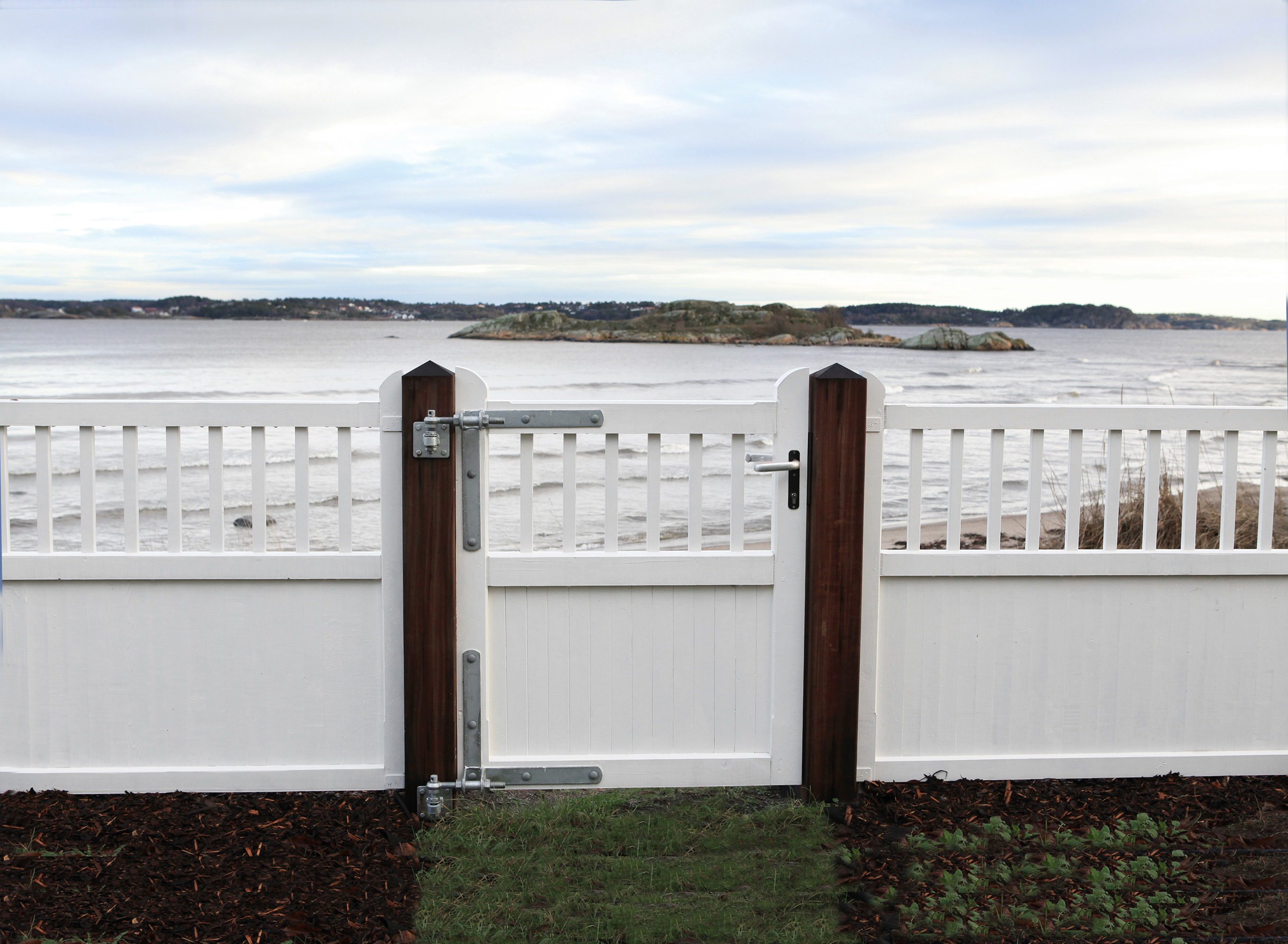 Im Vordergrund befindet sich das Tor des Country Garden. Im Hintergrund befindet sich ein See