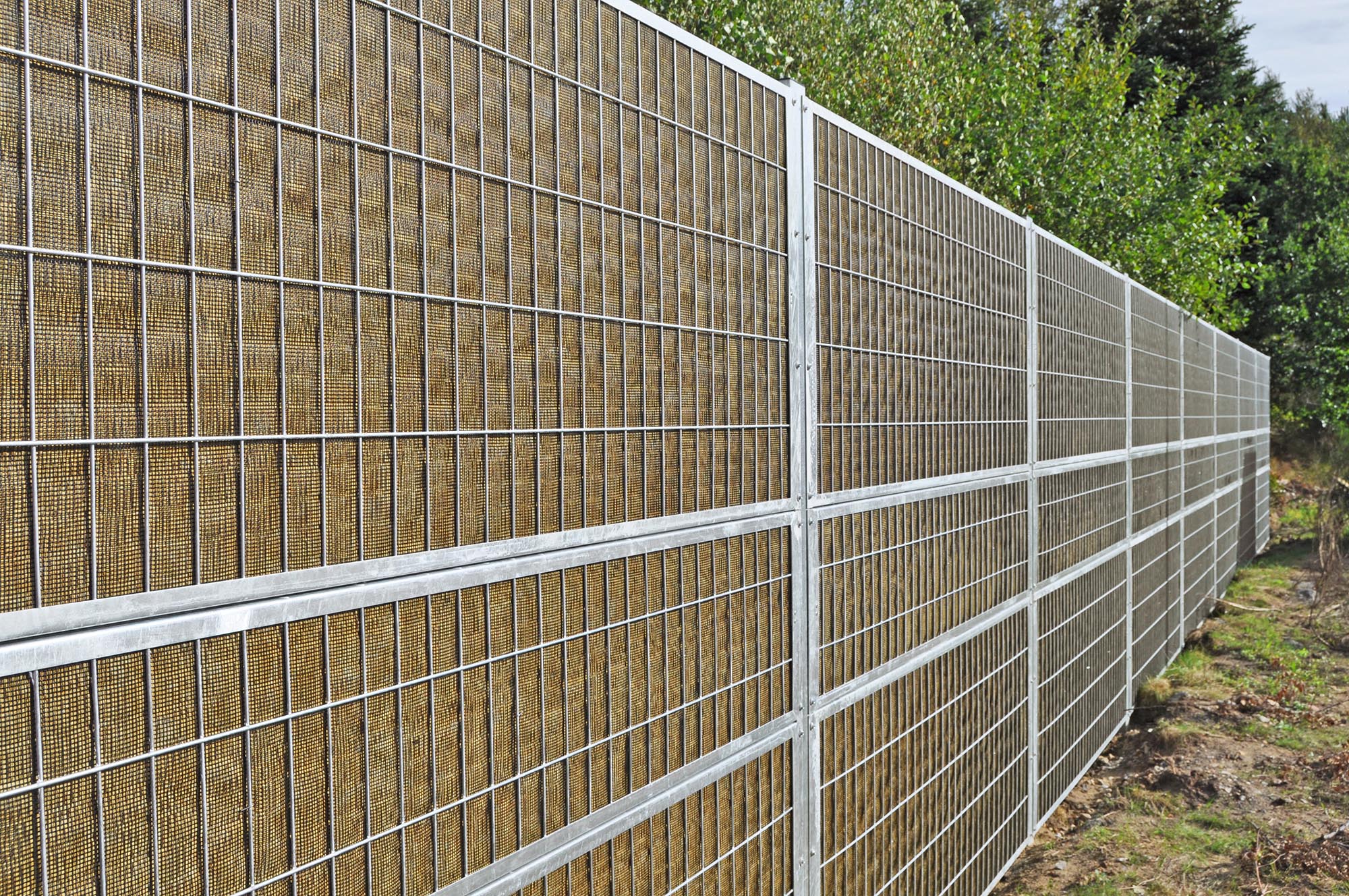 Noistop Essential Lärmschutzzaun mit verzinktem Stahlrahmen und Metallpaneelen, aufgestellt in einem grünen Gebiet.