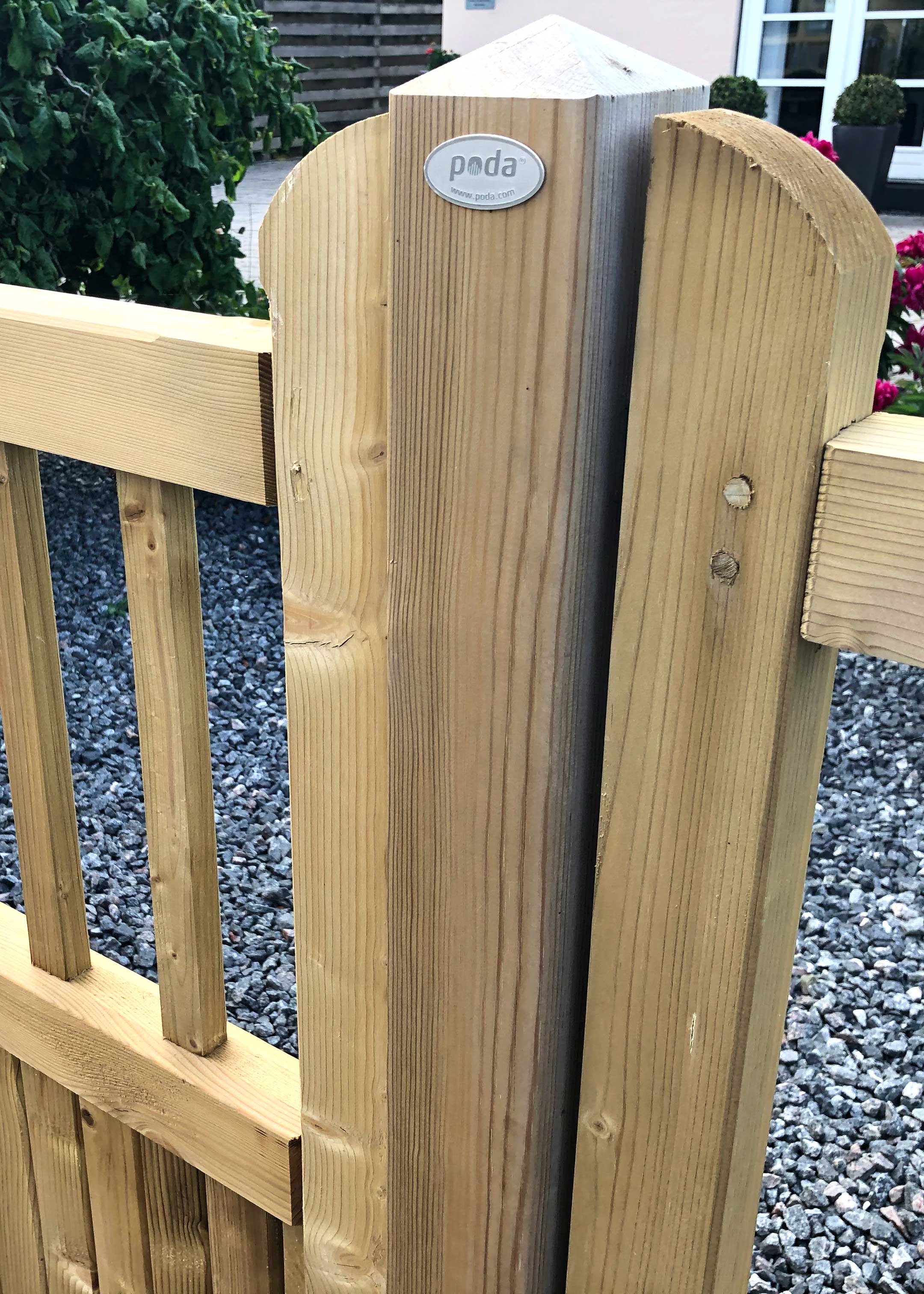 Ein Holzpfosten für den Country Garden-Zaun, mit einem Zaunteil auf beiden Seiten