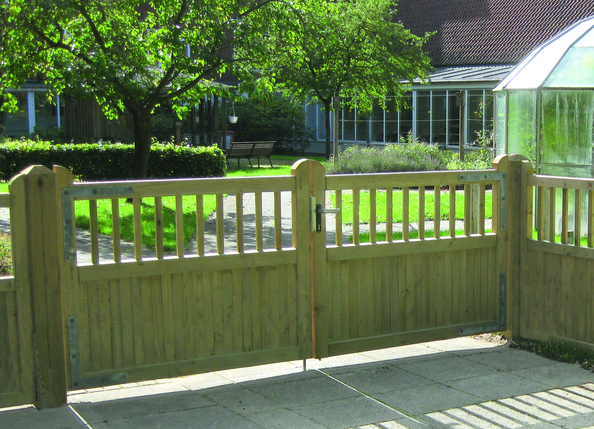 Im Vordergrund ist ein Country Garden, im Hintergrund ein Garten mit Gewächshaus