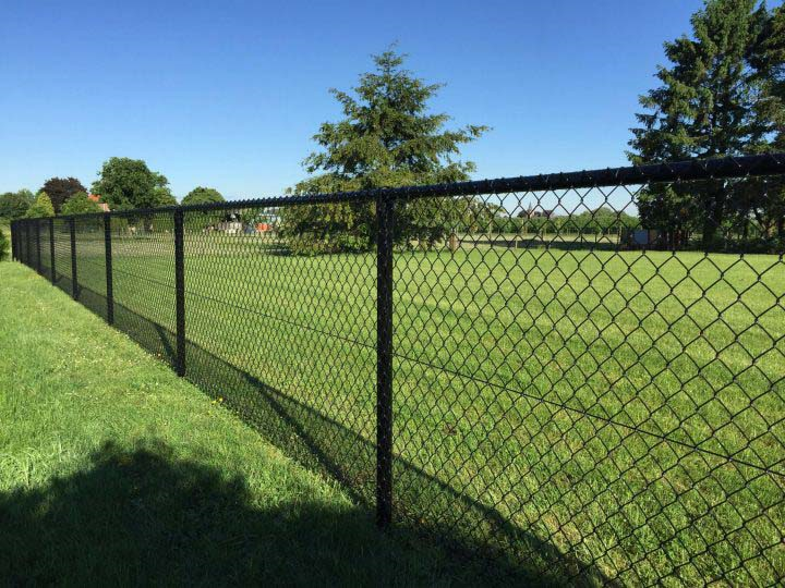Ein Maschendrahtzaun in einem Garten mit grünem Gras